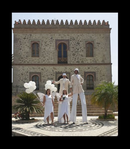 Zancudos vestidos de blanco recibiendo a los invitados frente a un palacio