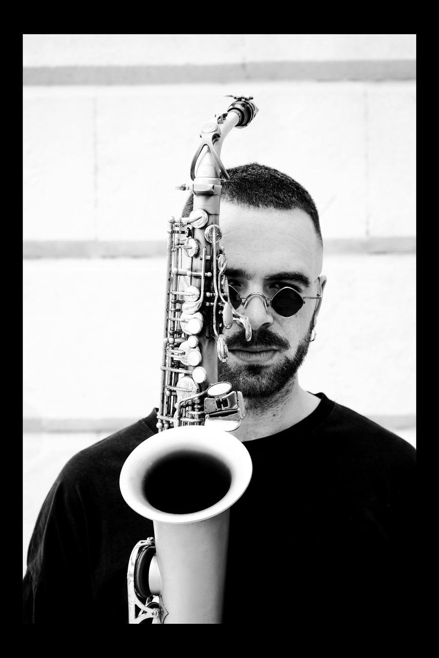 Saxofonista en blanco y negro tocando junto a una ventana