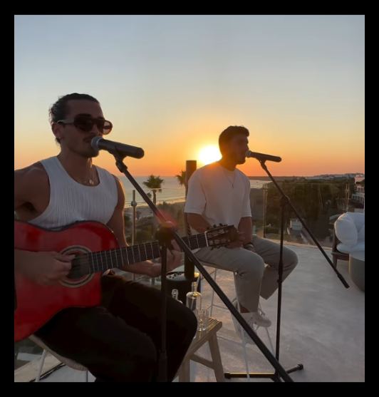 Dúo de música en vivo tocando al atardecer en una terraza frente al mar